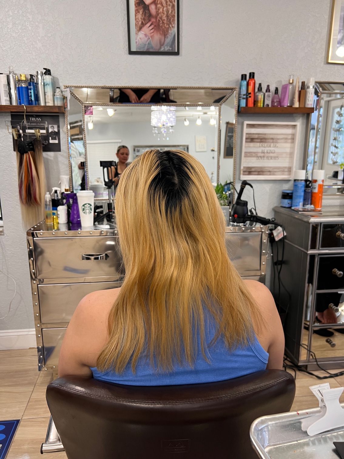 A woman with blonde hair is sitting in a chair in a salon.