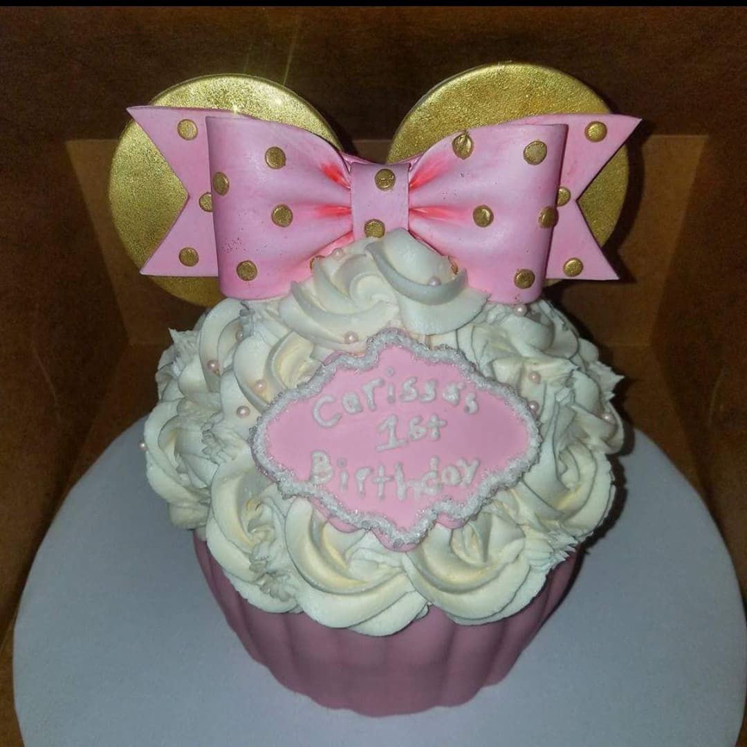 Giant pink cupcake decorated like Minnie Mouse for a 1st birthday.
