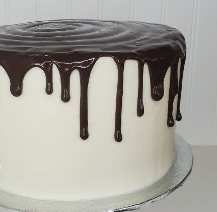 White frosted cake with chocolate ganache drip.
