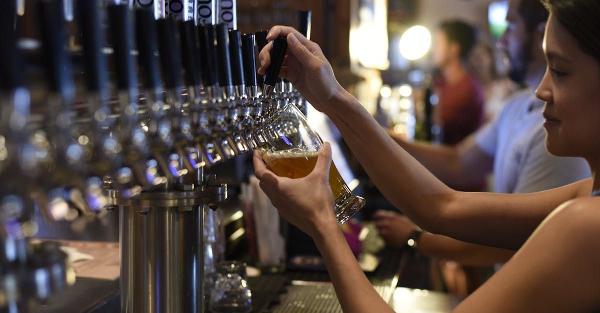 A woman is pouring beer into a glass at a bar.