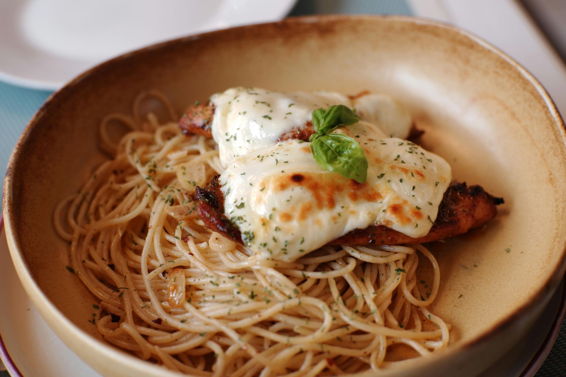 A bowl of spaghetti with meat and cheese on top.