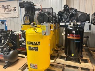 A bunch of air compressors are sitting on pallets in a room.
