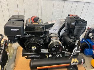 A black air compressor is sitting on top of a wooden table.