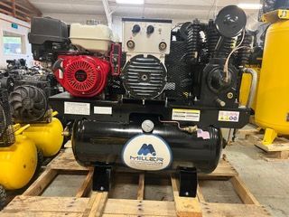 A large air compressor is sitting on top of a wooden pallet.