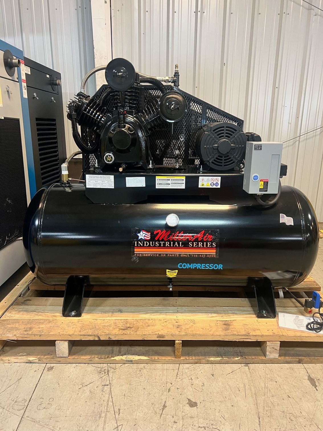 A large air compressor is sitting on top of a wooden pallet.
