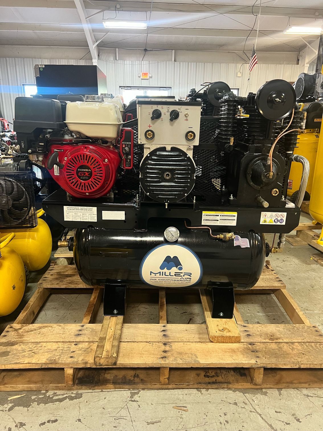 A large air compressor is sitting on top of a wooden pallet.