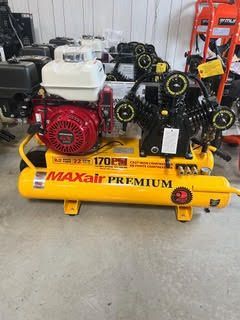 A yellow air compressor with a red engine is sitting on a concrete floor.