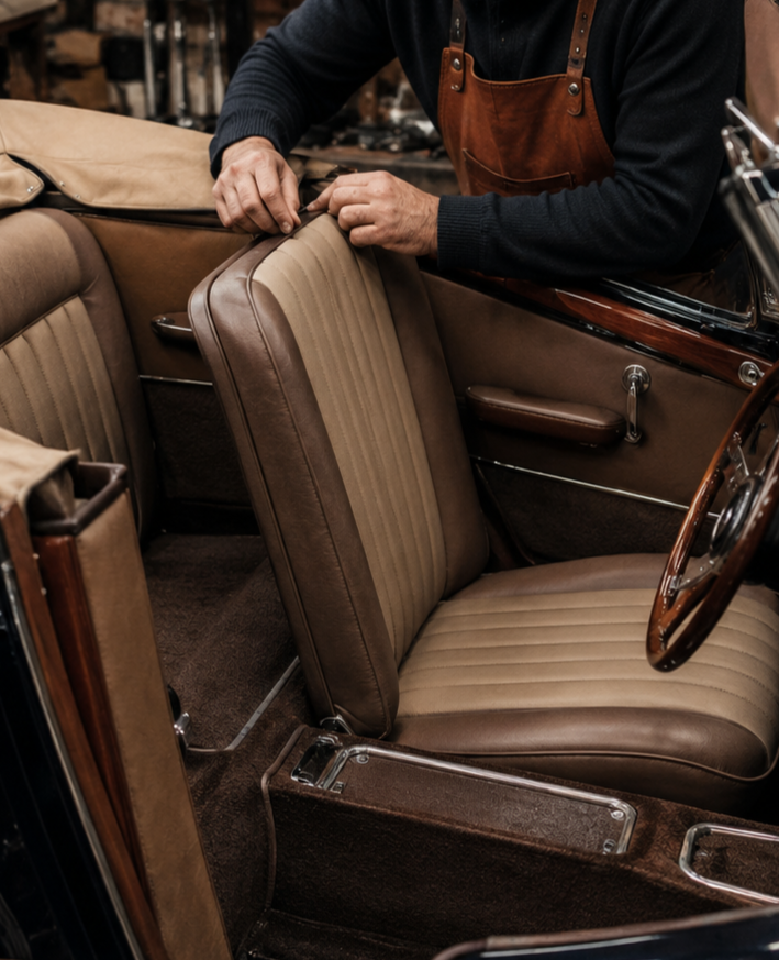 Una persona regola un sedile in pelle color cuoio all'interno dell'abitacolo di un'auto d'epoca.