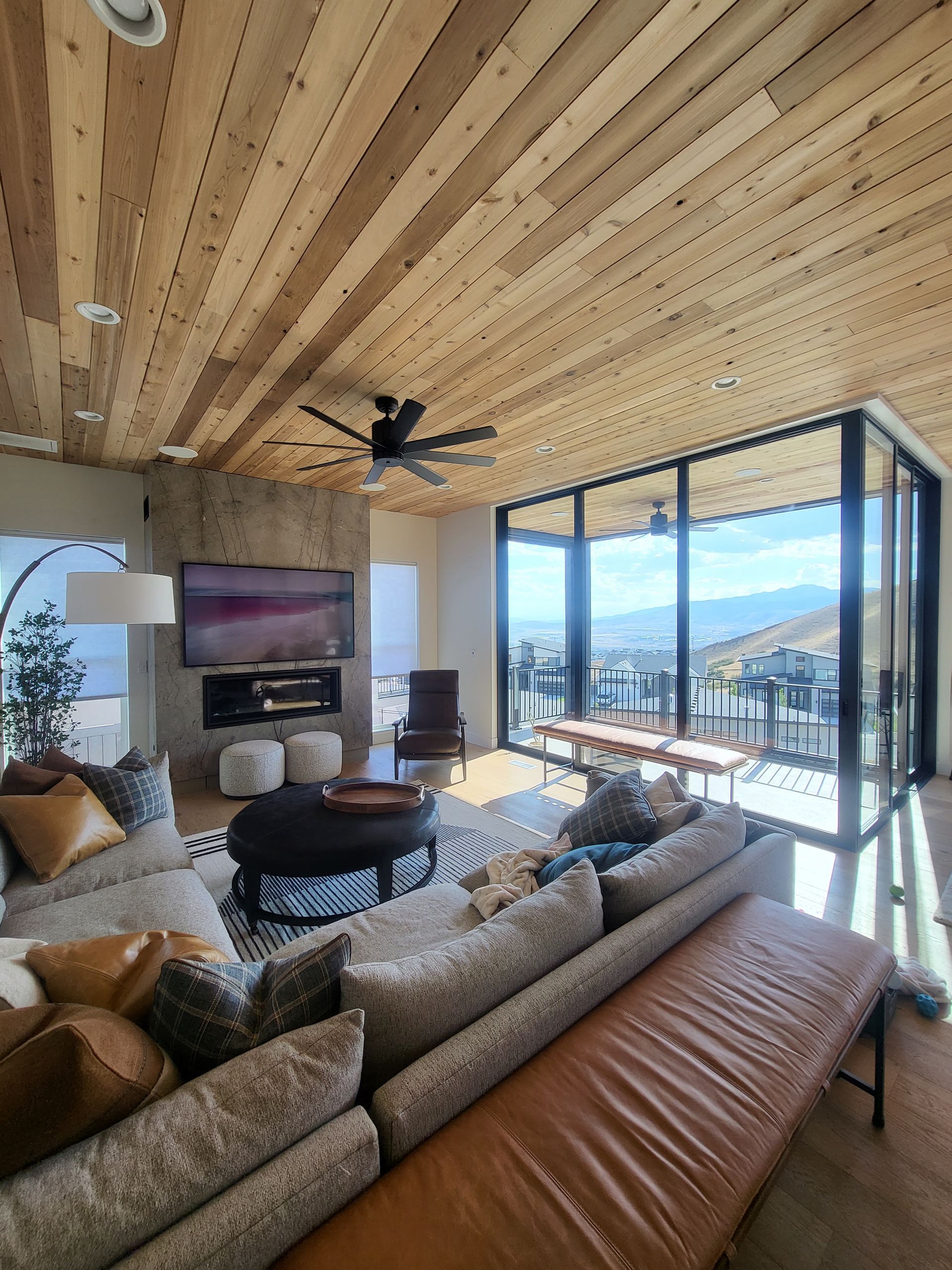 Modern, bright living room with white walls, wood floors, and a glass door to a balcony.