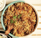 Chicken biryani in a teal bowl, garnished with cilantro, with a side of white yogurt.