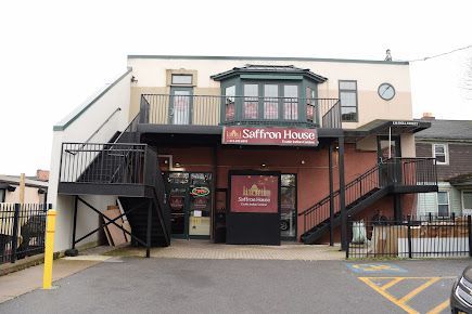 Saffron House restaurant exterior with two-story building, outdoor staircases, and signage. Brown and beige tones.