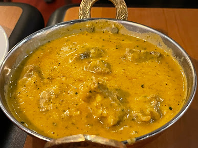 Yellow creamy curry in a metal bowl, likely an Indian dish.