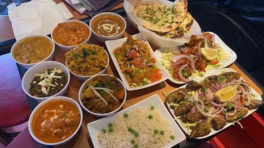 Indian food spread: various curries, rice, naan, tandoori dishes, and chutneys.