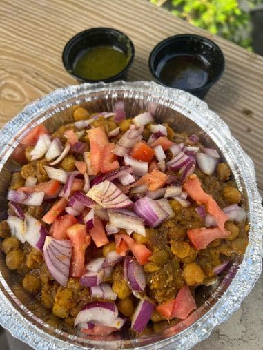 Chickpea chaat with chopped tomatoes and onions, served with green and brown sauces.