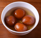 Bowl of gulab jamun in syrup; brown, round dumplings.