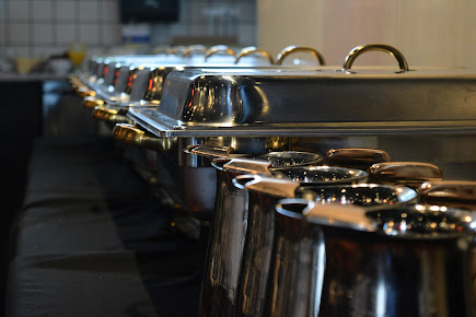 Row of stainless steel chafing dishes at a buffet, lids closed, ready for food service.