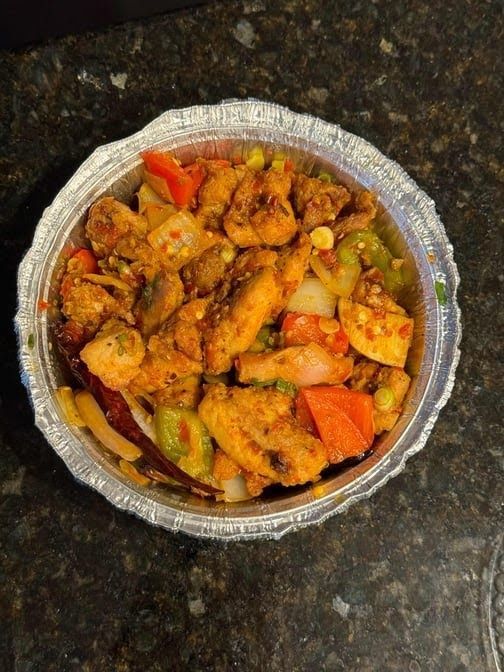 Chicken fajita bowl with red and green peppers, onions, and corn in a foil container.
