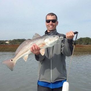 Smiling person holding a large fish on a boat on calm water