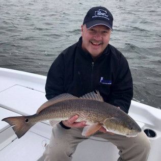 Man on a boat holding a large fish over the water