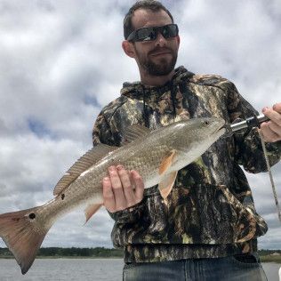 Person holding a large fish outdoors under a cloudy sky