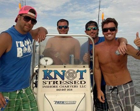 Four men posing on a boat by a sign reading “KNOT STRESSED CHARTERS LLC”