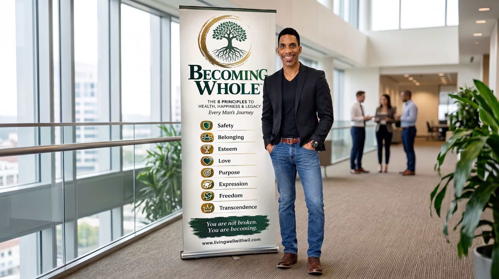 Man standing beside a banner in a cozy office lounge with plants, bookshelves, and a leather chair.