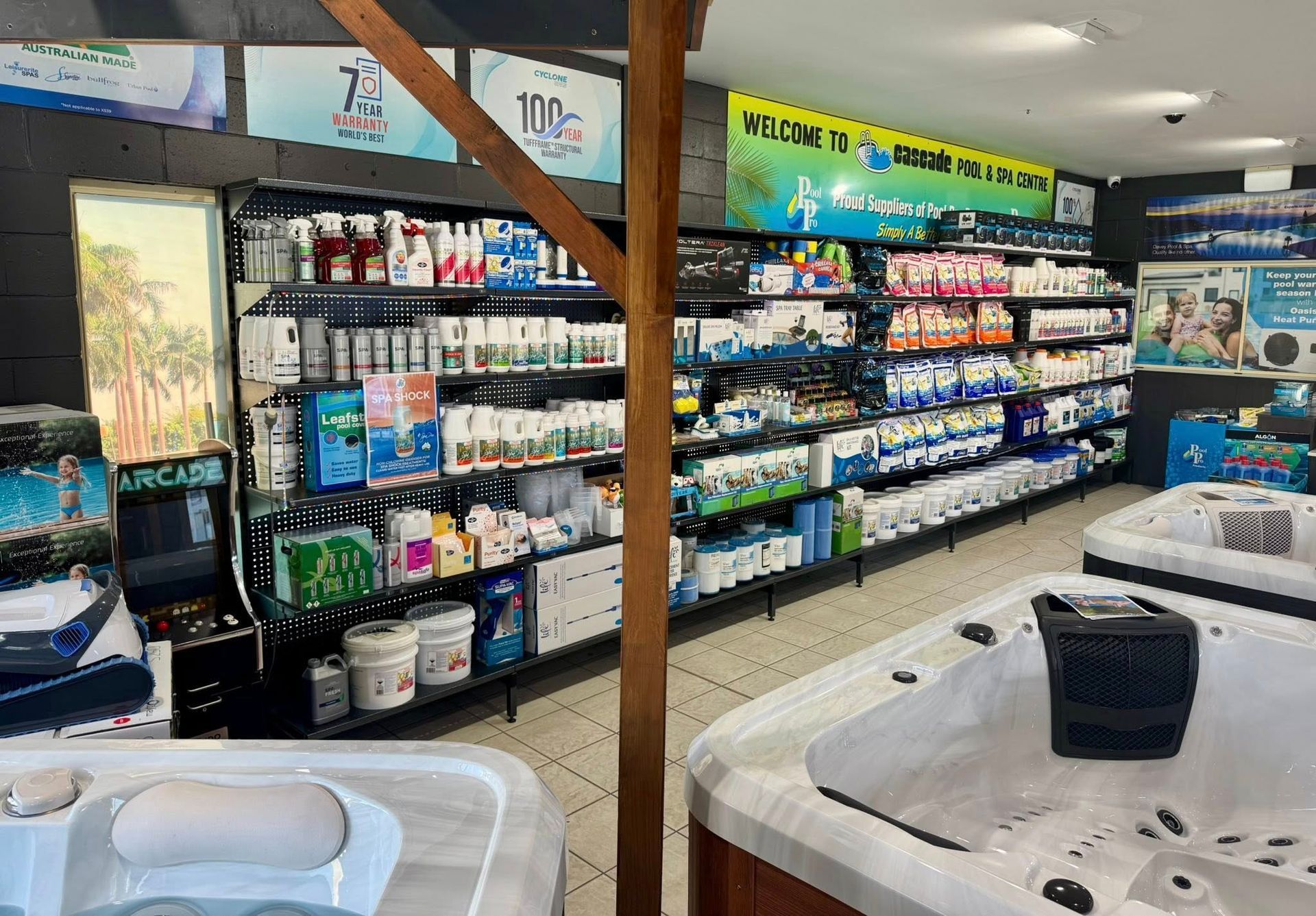 A Spa Store Interior With Hot Tubs and Shelves Stocked With Pool Chemicals — Cascade Pool & Spa Centre in Laurieton, NSW