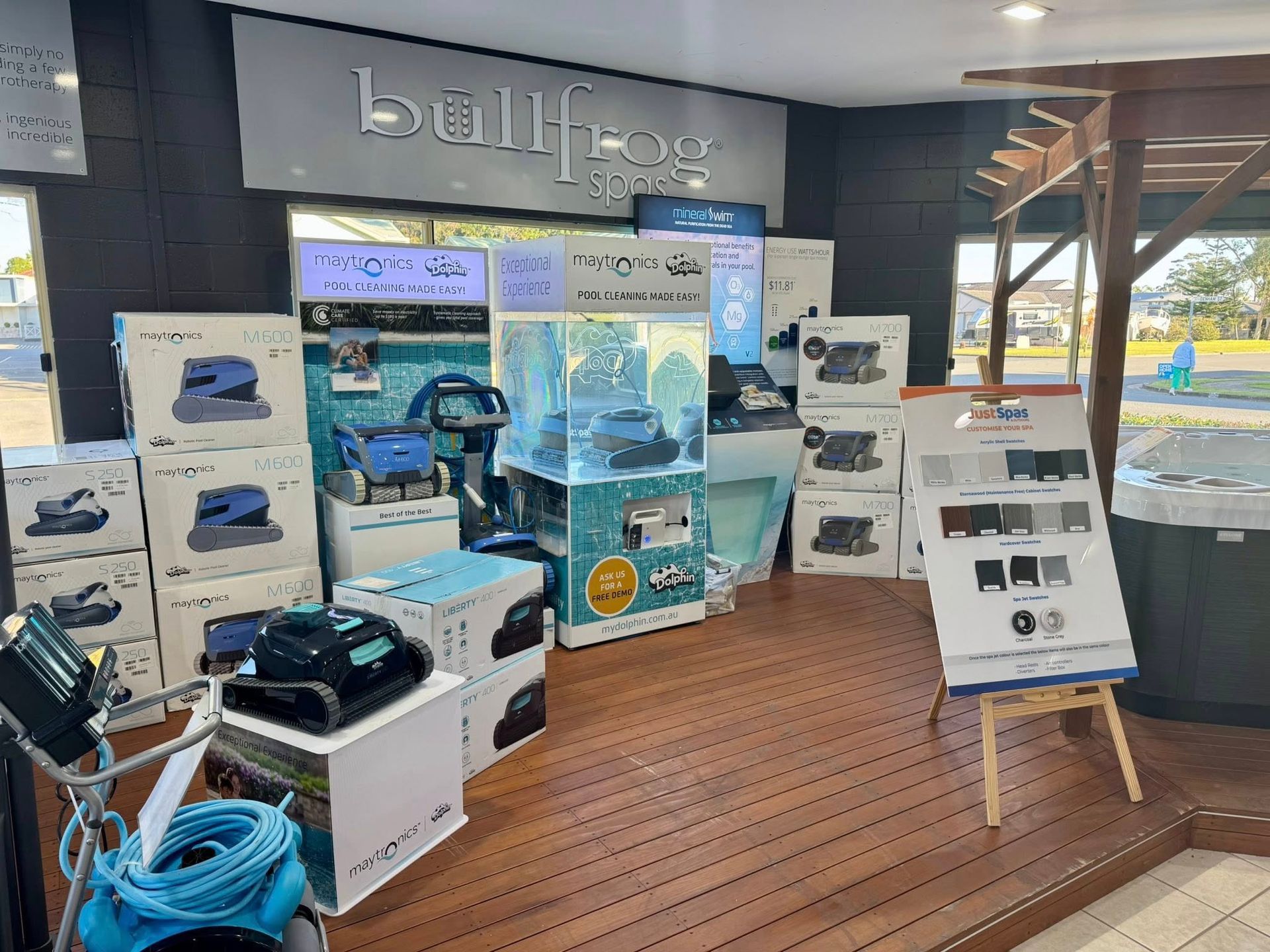 A Pool Equipment Store Display With Boxes, Signs, and a Robot Cleaner on Wooden Flooring — Cascade Pool & Spa Centre in Wauchope, NSW