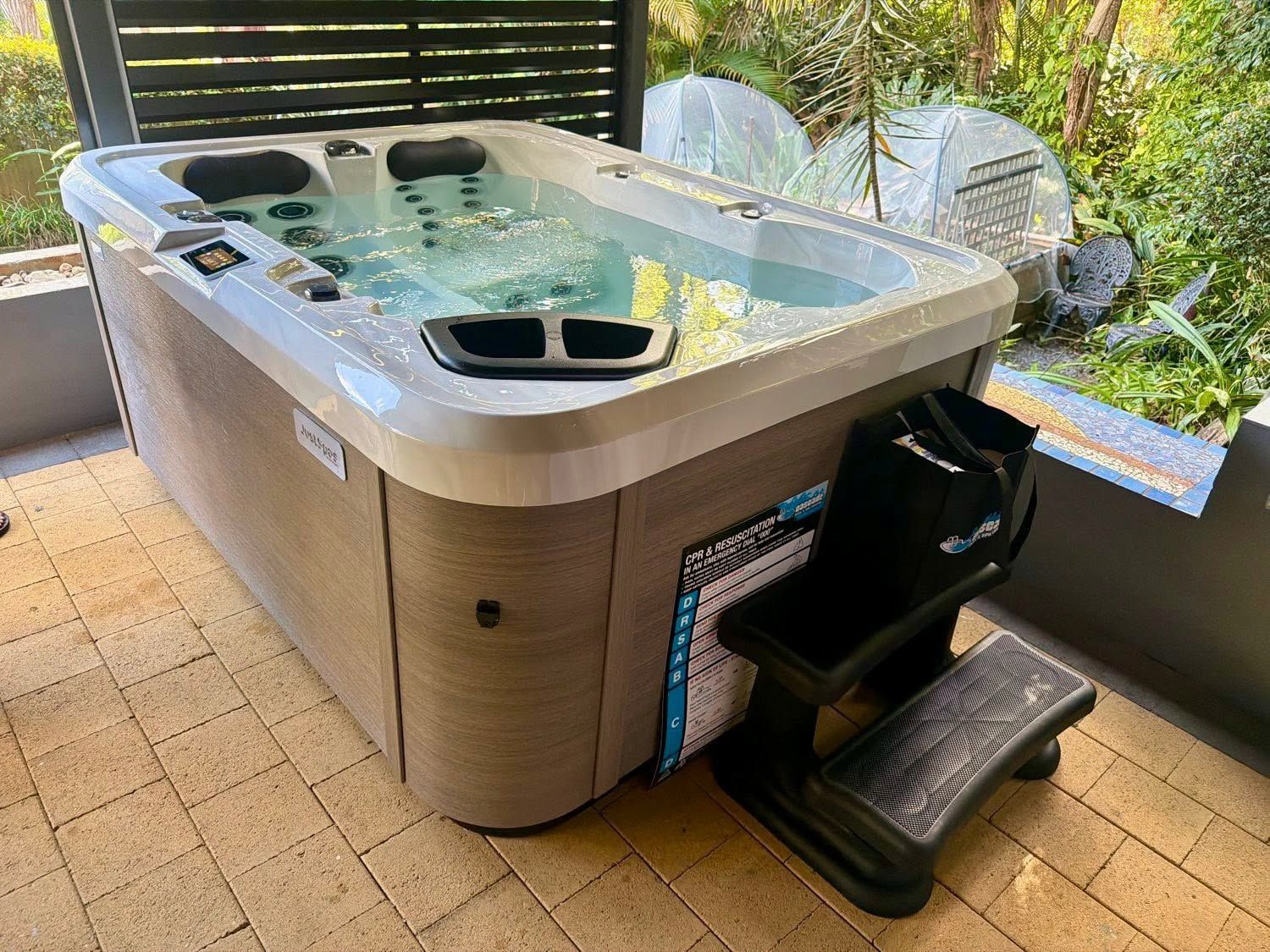 Outdoor Spa With Bubbling Water and a Step Stool on a Patio — Cascade Pool & Spa Centre in Port Macquarie, NSW