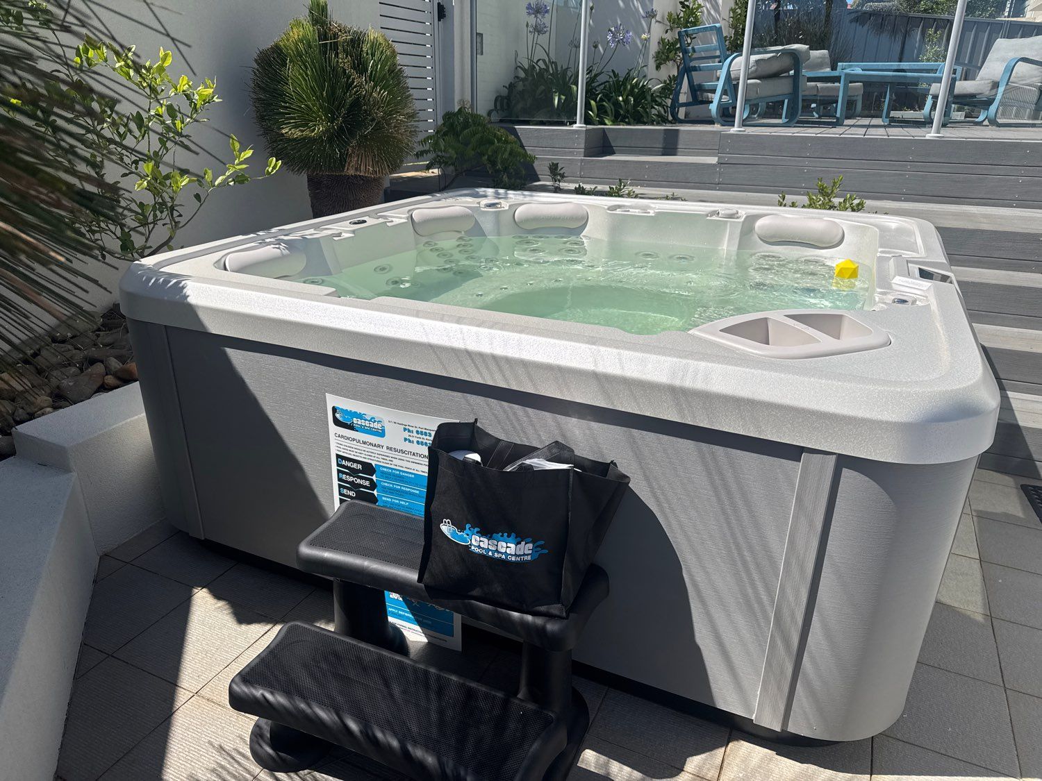 Outdoor hot tub in a patio area with water jets and a black massage chair in front — Cascade Pool & Spa Centre in Port Macquarie, NSW