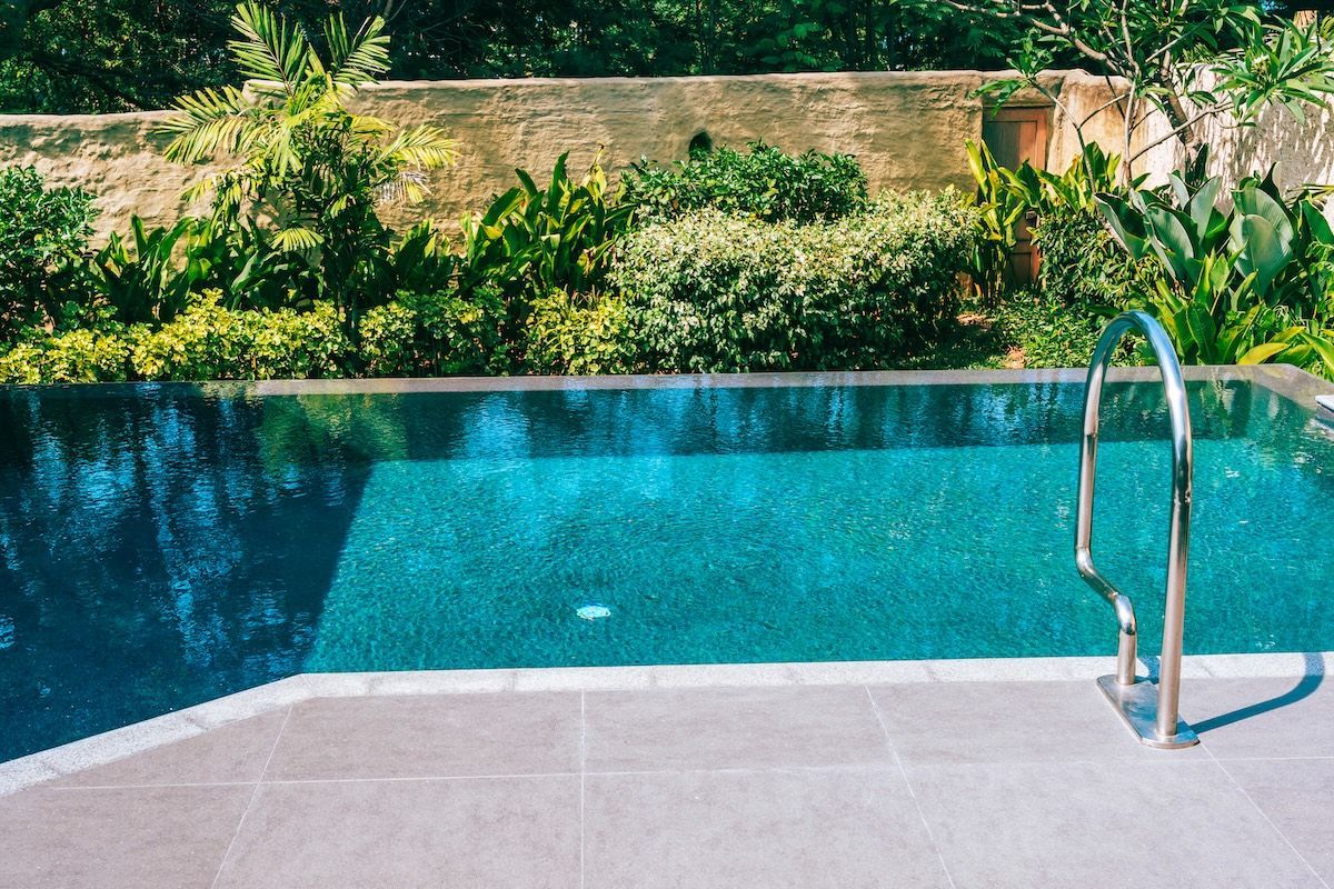 A swimming pool with turquoise water, a stainless steel ladder, and lush greenery in the background — Cascade Pool & Spa Centre in Port Macquarie, NSW