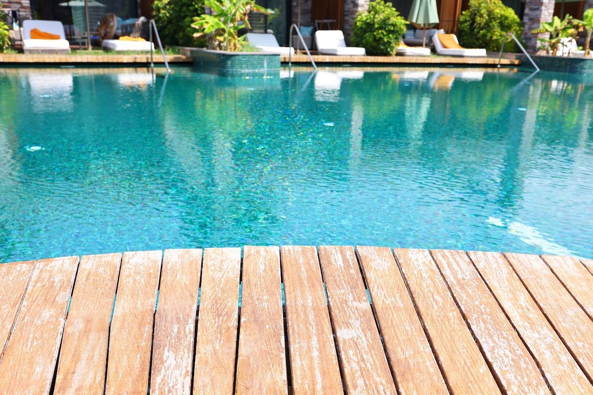 Wooden deck overlooking a turquoise swimming pool with lounge chairs and green foliage in the background — Cascade Pool & Spa Centre in Port Macquarie, NSW