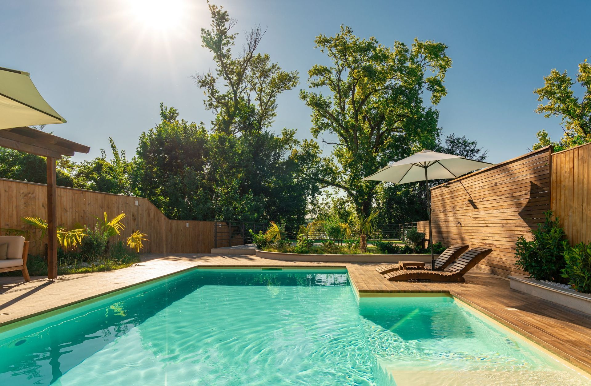 A Swimming Pool With Wooden Deck, Lounge Chairs, and Umbrella — Cascade Pool & Spa Centre in Port Macquarie, NSW
