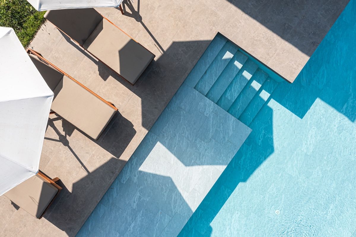 Overhead view of a pool with stairs, patio with lounge chairs and umbrella casting shadows — Cascade Pool & Spa Centre in Port Macquarie, NSW