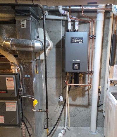 Basement utility room with furnace, water heater, and wall-mounted boiler amid exposed pipes and ducts