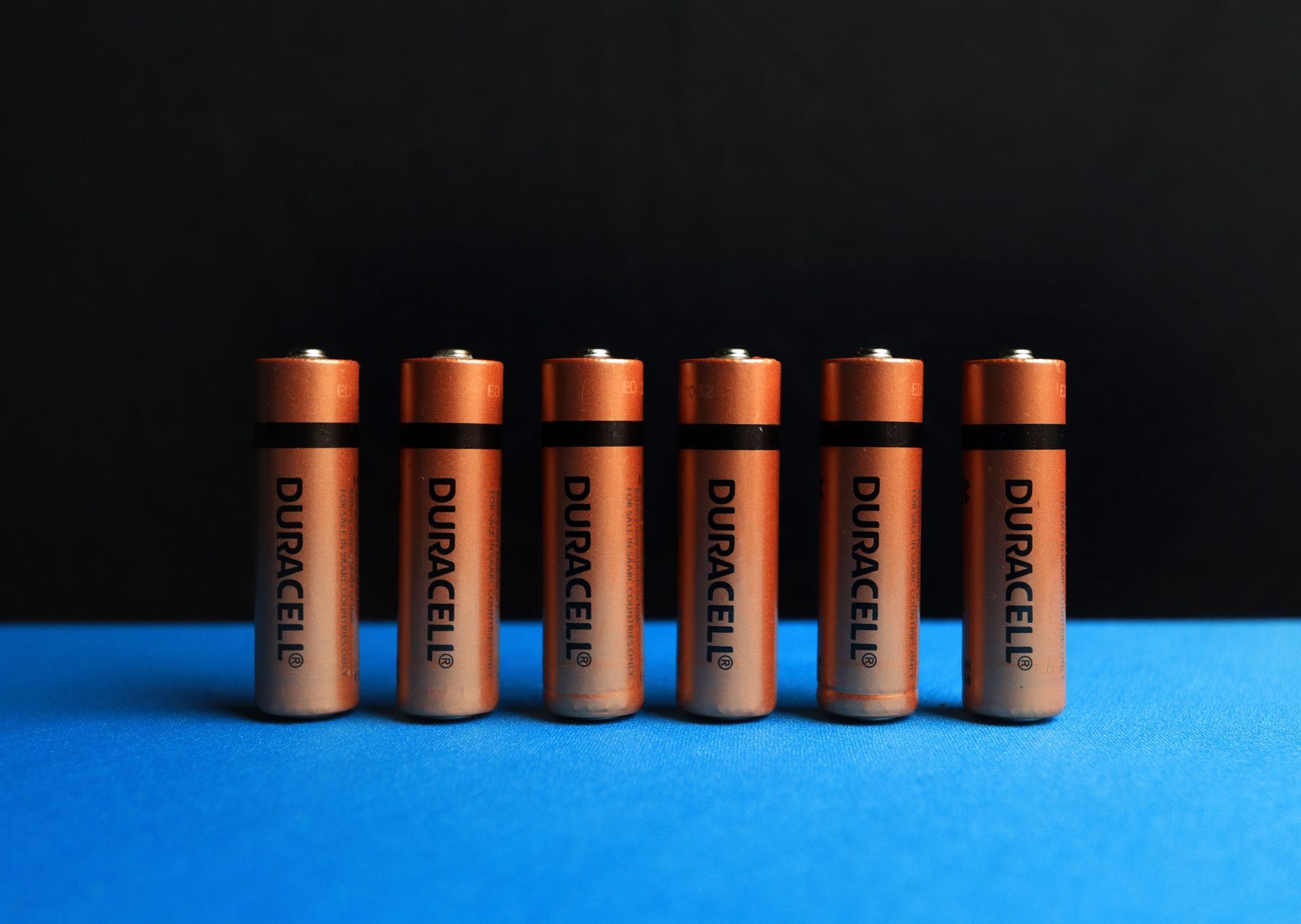 Household batteries lined up on a dark background.