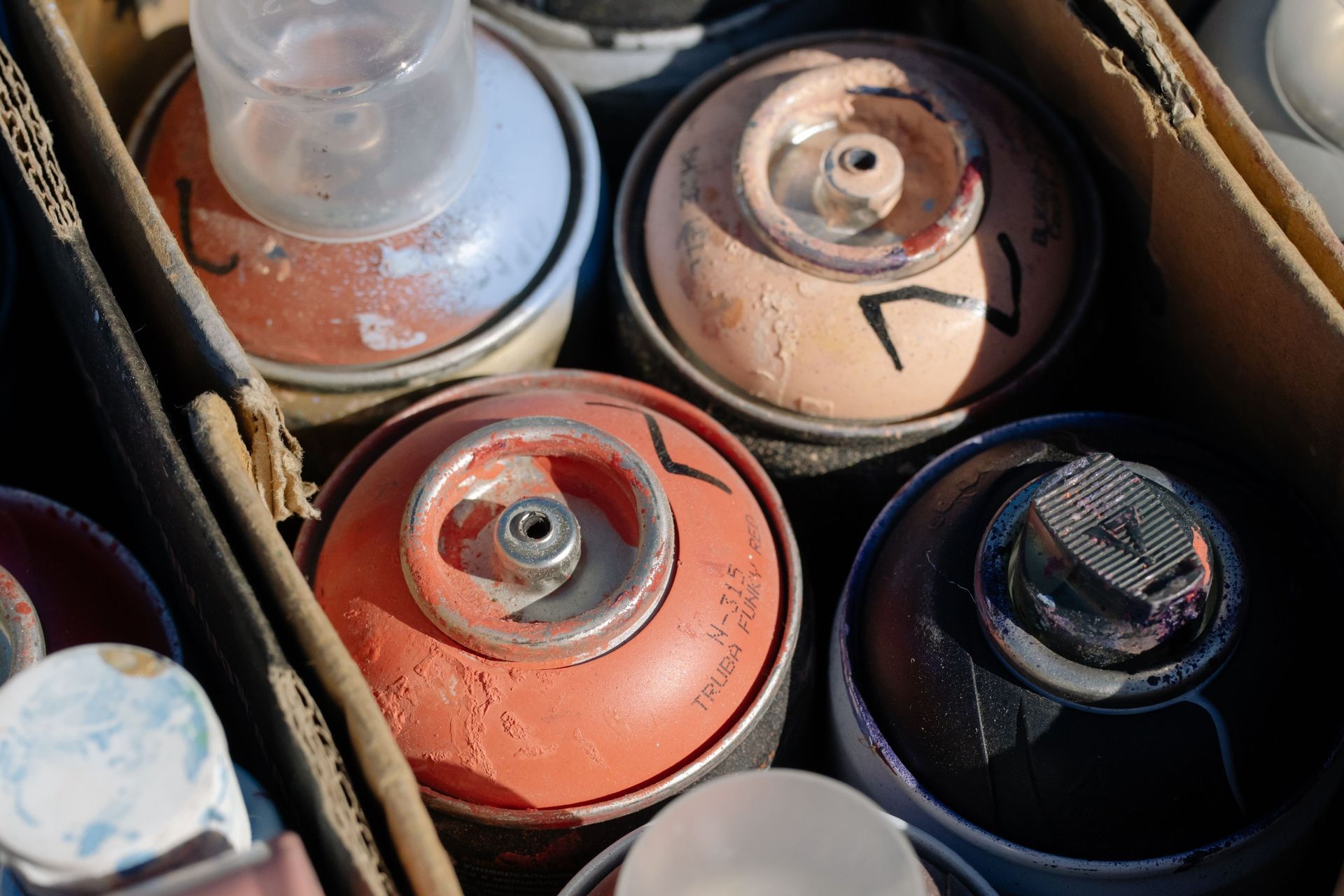 Used aerosol paint cans gathered together for identification before disposal.