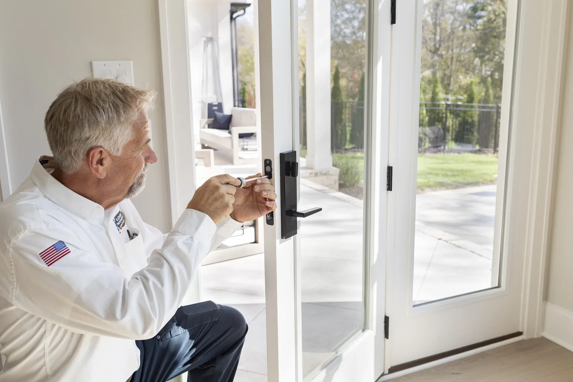 A person installing a door handle on a glass door. Outdoors setting with sunlight.