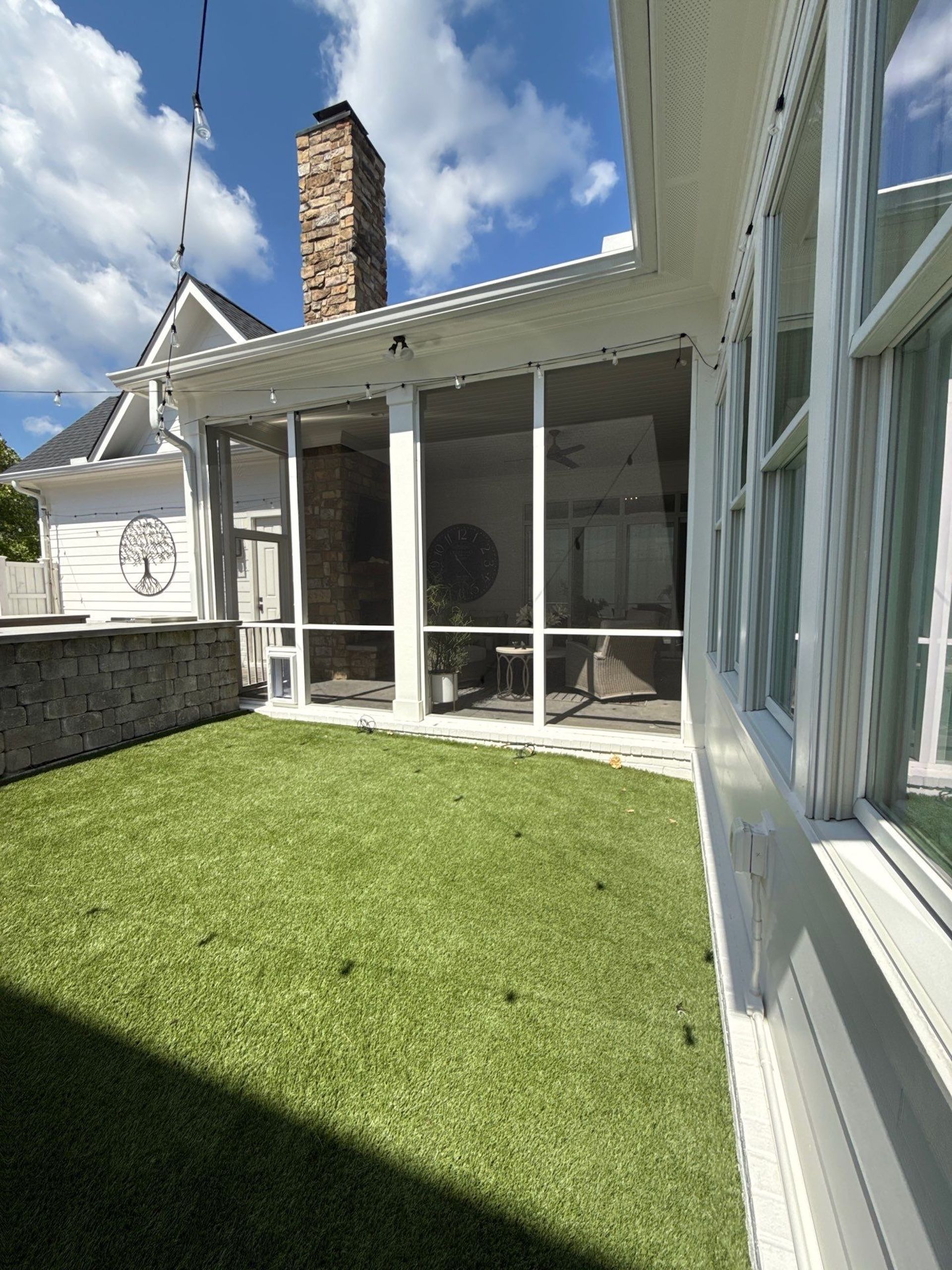 Screened porch with white trim and a green lawn under a partly cloudy sky.