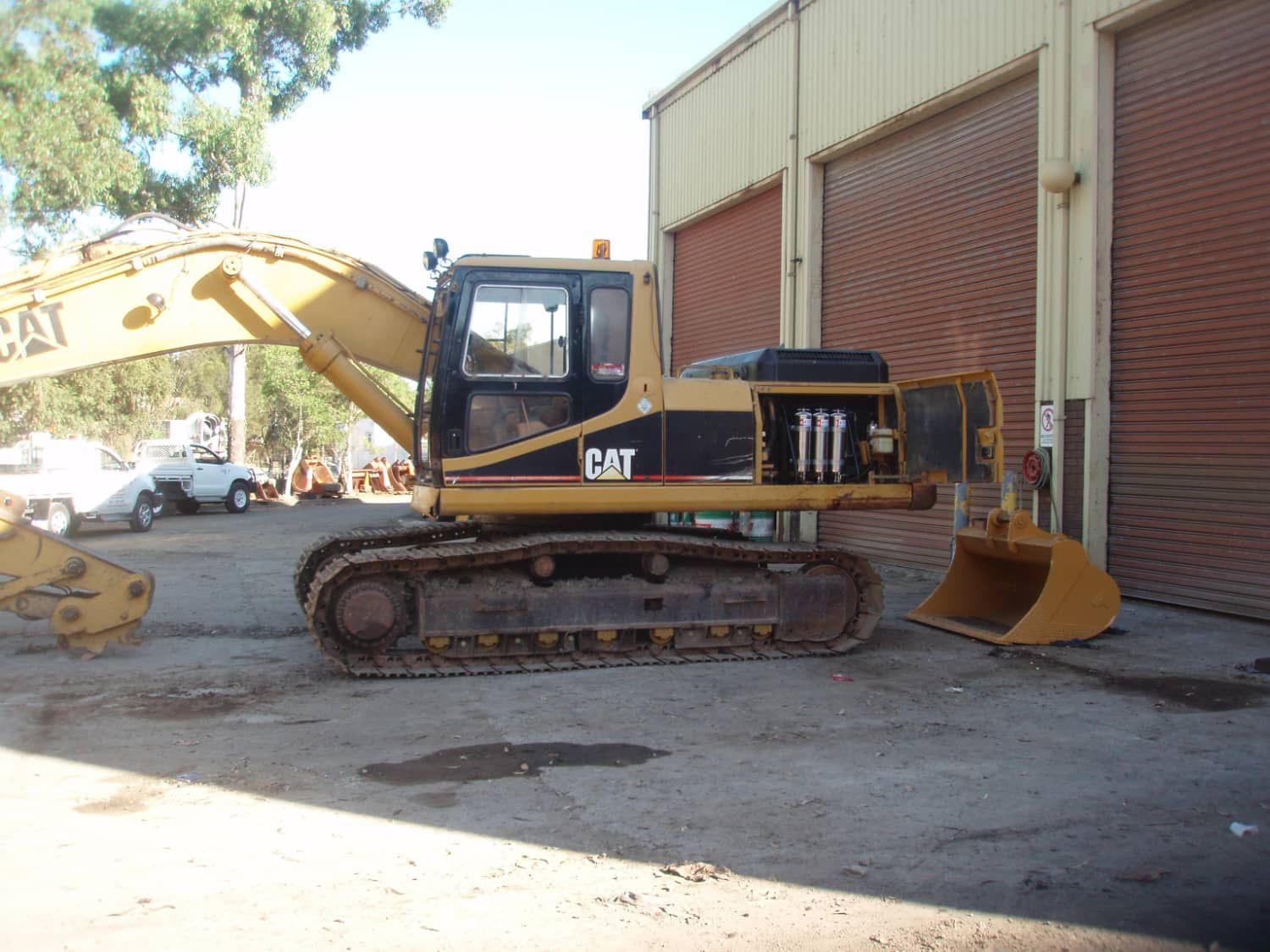 A cat excavator is parked in front of a building
