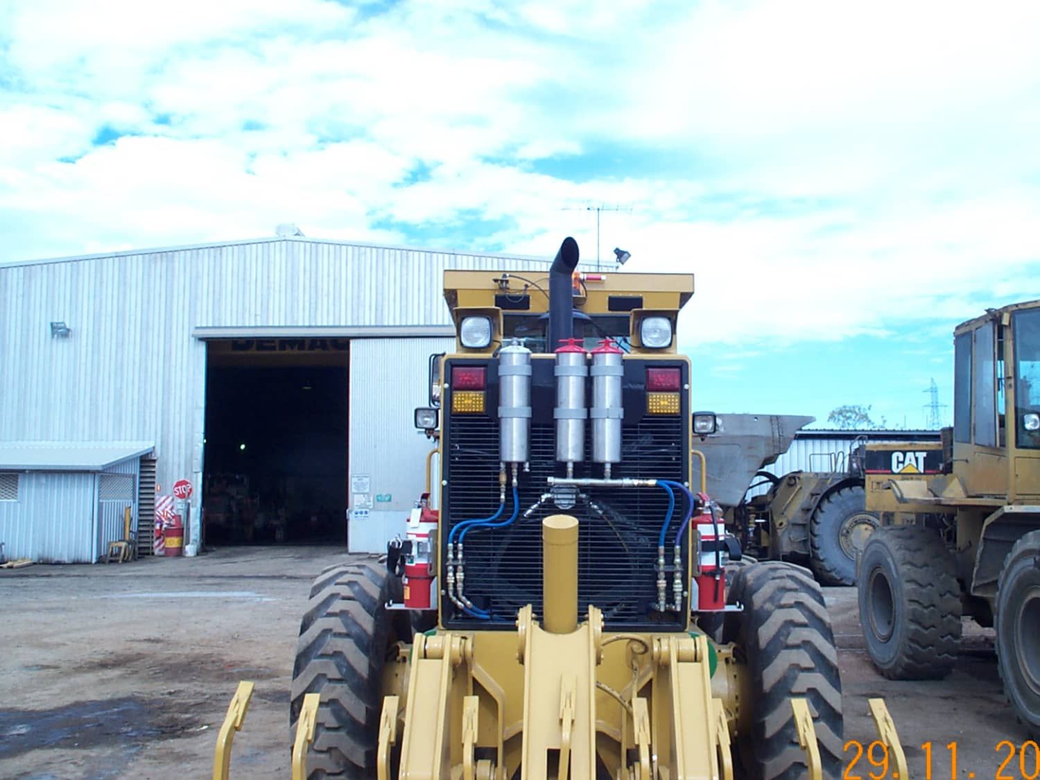 A yellow caterpillar tractor is parked in front of a building