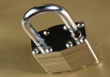 Closed brass padlock with a silver shackle on a tan surface
