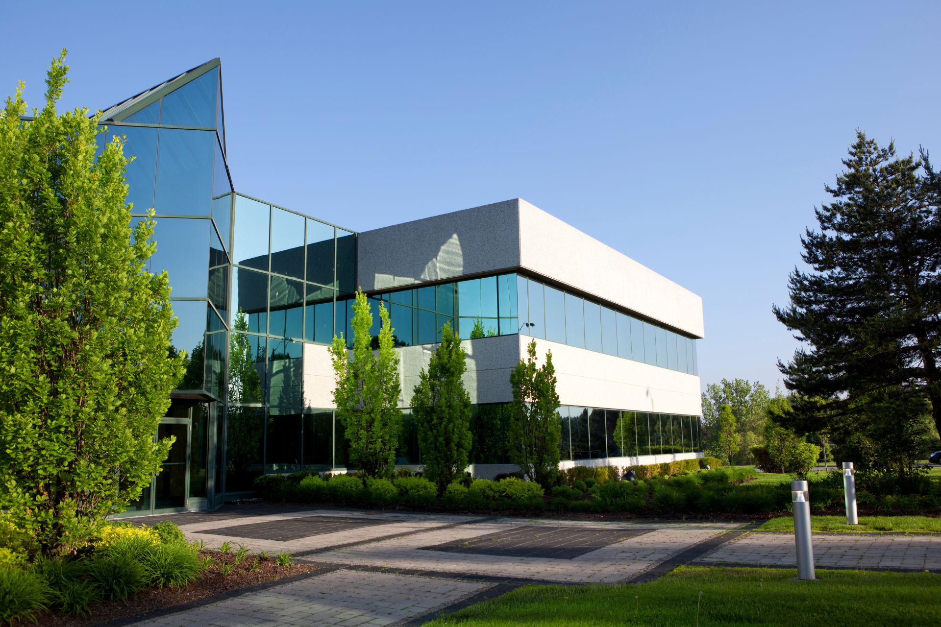 Modern two-story brick-and-glass building with landscaped entrance under a blue sky