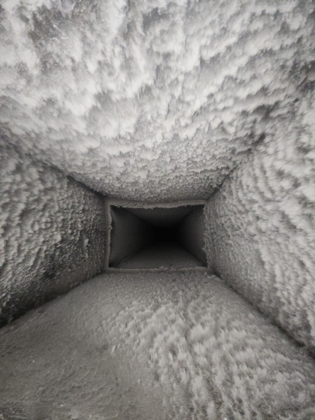 Interior of a gray, frost-covered air duct or vent, viewed looking down the tunnel