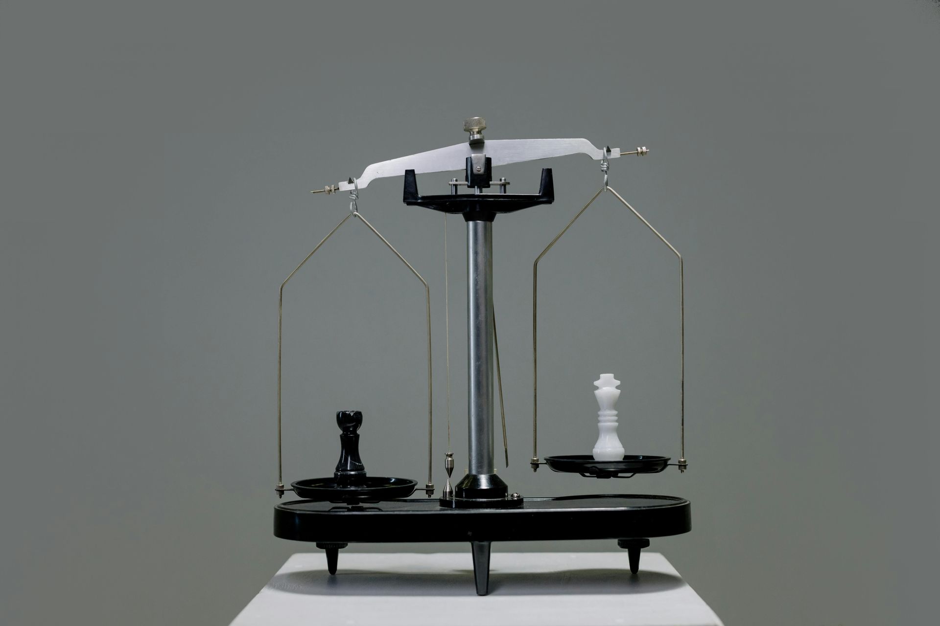 A balance scale with a black chess knight on one side and a white pawn on the other.