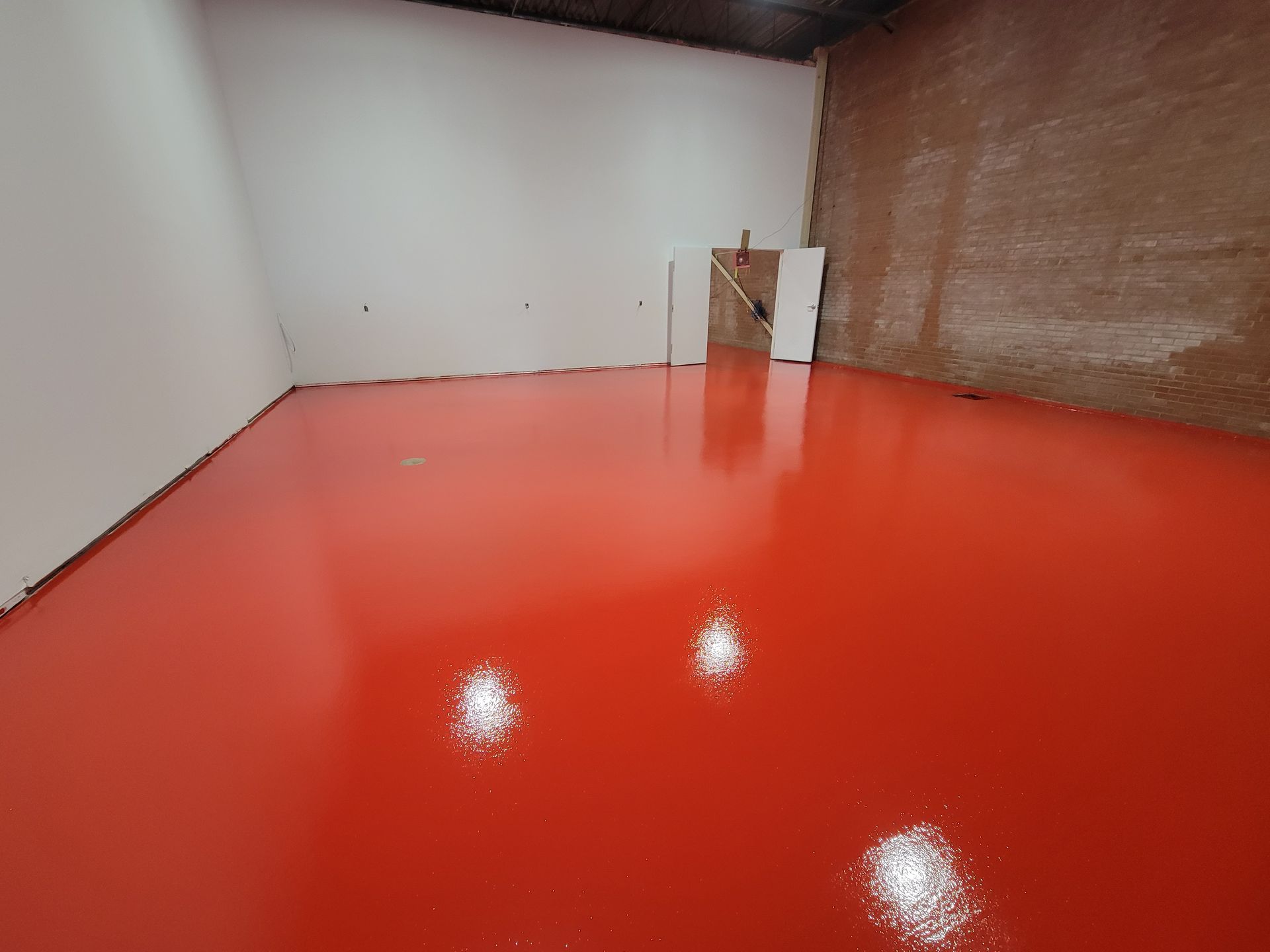 Sol époxy rouge dans une pièce vide avec des murs blancs et marron texturés.