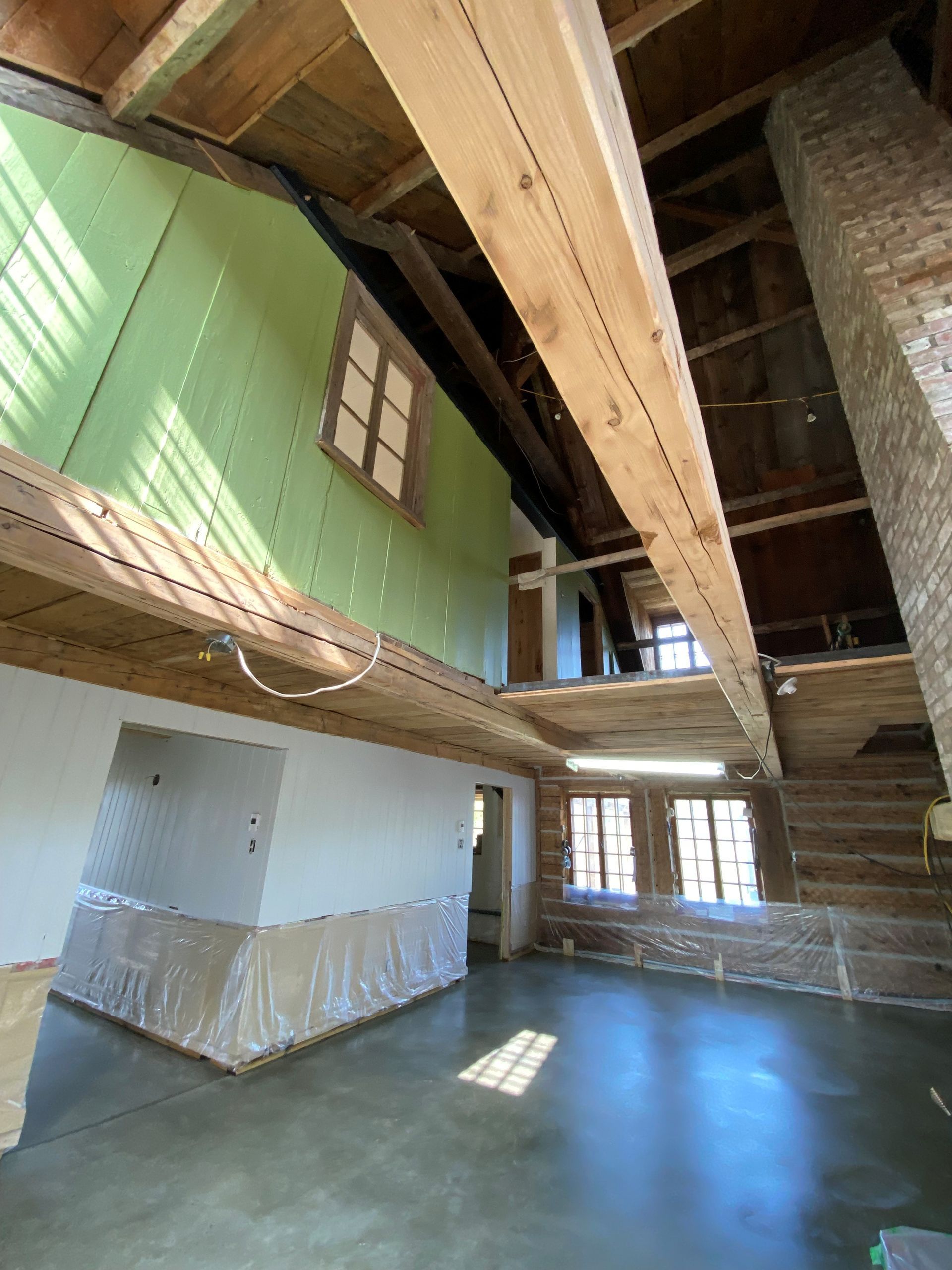 Vue intérieure d'une pièce avec poutres apparentes, mezzanine et mur isolé végétal.
