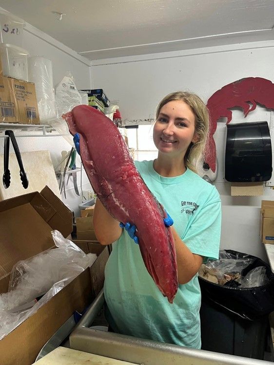 A woman is holding a large piece of meat in a kitchen.