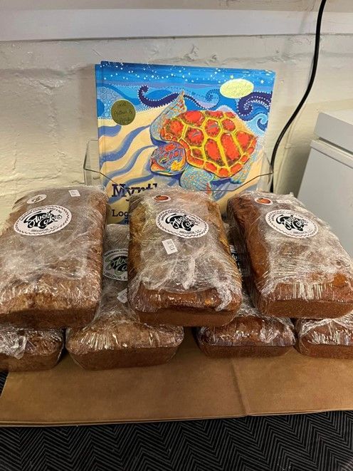 A bunch of loafs of bread are sitting on a table next to a painting of a sea turtle.