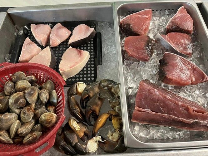 A tray of seafood including shrimp , mussels and tuna on ice.